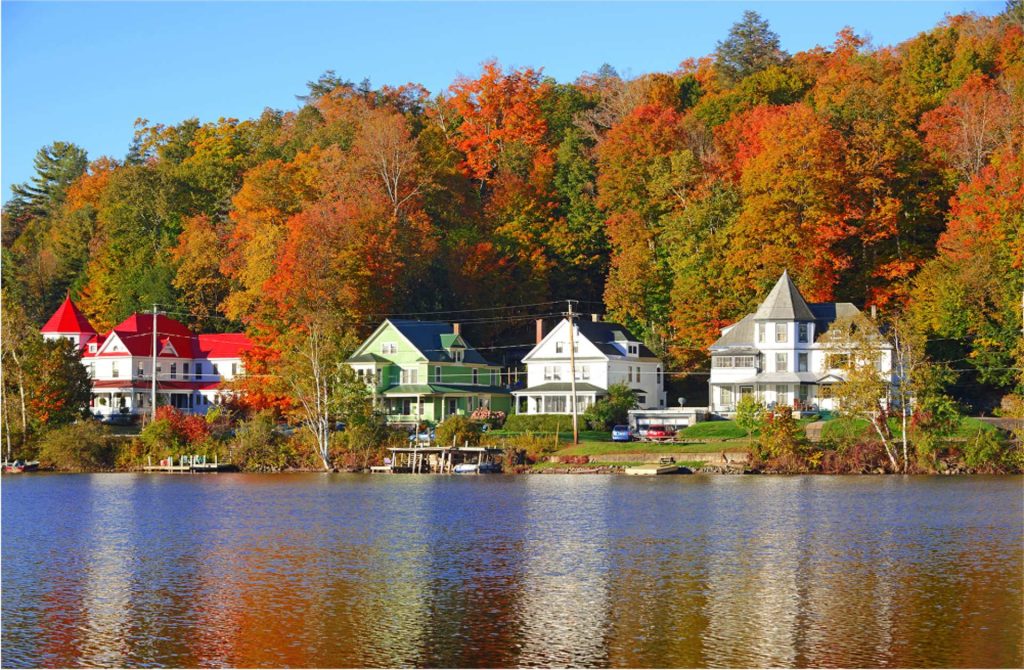 Scenic lakefront residential homes surrounded by fall foliage, evoking the diverse real estate settings Seward & Seward serves in the downstate New York area.