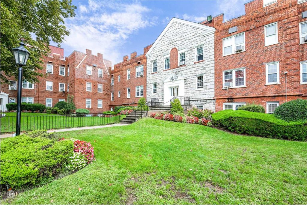 Red brick cooperative residence with manicured lawn, highlighting Seward & Seward’s specialization in co-op and real estate law in Long Island and New York City